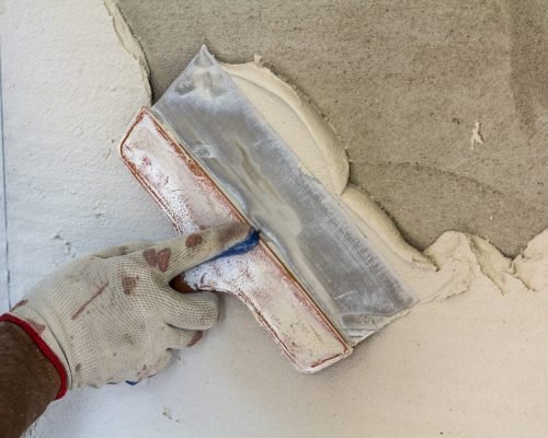 Renovation workers hand plastering the wall